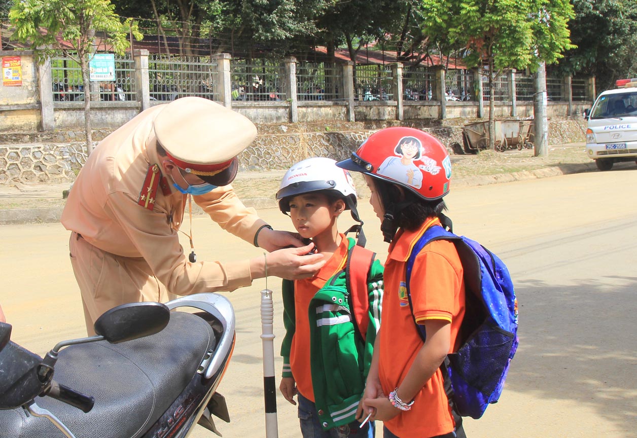 Cán bộ Phòng Cảnh sát Giao thông (Công an tỉnh) hướng dẫn cách đội mũ bảo hiểm cho học sinh.
